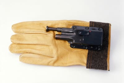 Hansikas jonka päällä on hansikkaan sisälle piilotettava pistooli. 