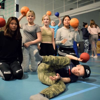 Åtta ungdomar  uppställda i en gympasal med bollar i händerna.
