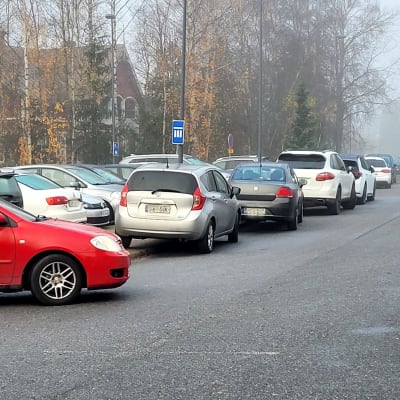 Många parkerade bilar längs en väg. 