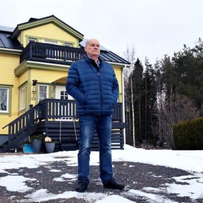 Birger Ekman står framför sitt gula hus i lite smått vinterväder.
