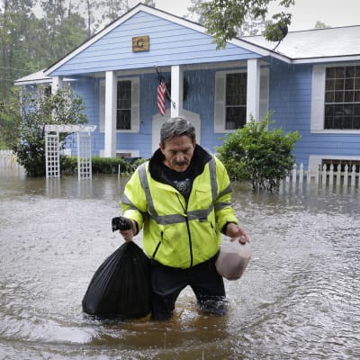 mies kantaa tavaroitaan tulvassa