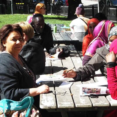 pakolaisia suomen kielen kurssilla puistossa