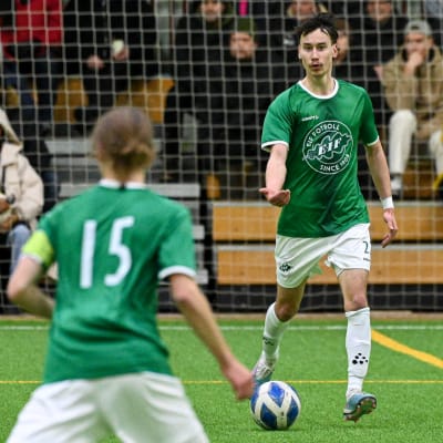 Två fotbollsspelande män i gröna kläder i en innehall.