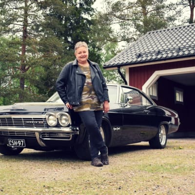 Mona Söderblom framför sin Cheva Impala 1966, en klassisk svart amerikansk bil