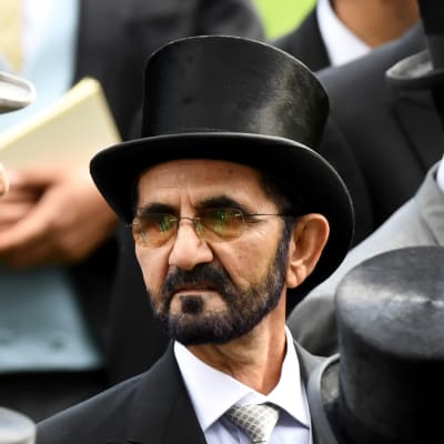 Man i hatt omgiven av andra svartklädda män i hatt.