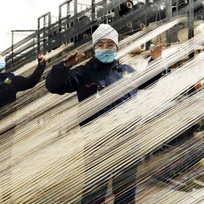 Työntekijöitä mattojen tuotantolinjalla Urumchissa, Xinjiangissa.