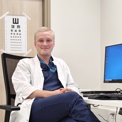 Oskari Lehtonen hymyilee valkotakissa työpöytänsä äärellä Nokian terveysasemalla.