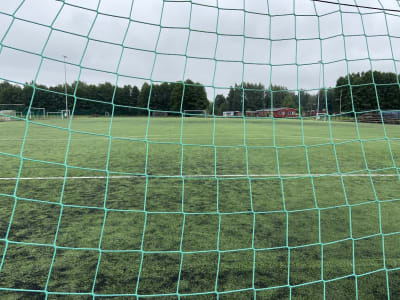 Fotbollsplan fotograferade mellan målets nätmaskor. 