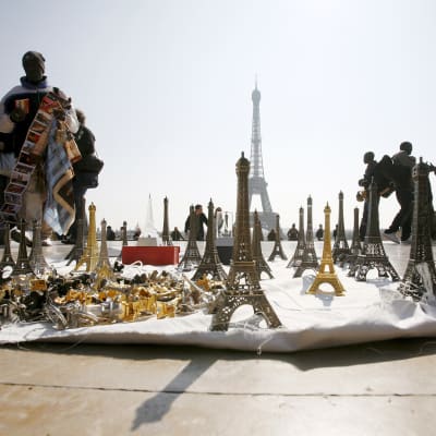 Katukauppiaat myyvät turisteille Eiffel-tornin pienoismalleja Pariisissa.