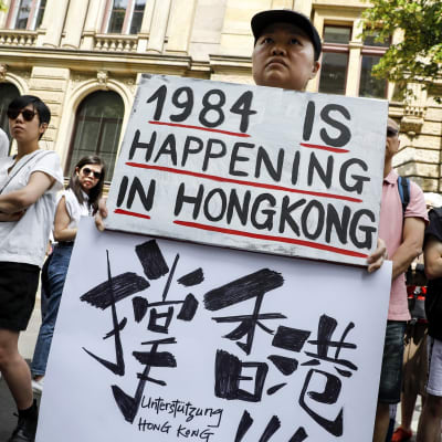 Berliinissä mielenosoittajan kyltissä luki "1984 tapahtuu Hongkongissa". Kyltti viitannee George Orwellin 1984 -romaaniin, joka kuvaa kaikkea valvovaa yhteiskuntaa. 