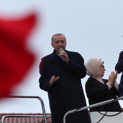 Recep Tayyip Erdoğan puhuu kannattajilleen korokkeella, etualalla punainen Turkin lippu.