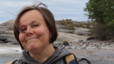 Annika Rautoma är språkstöd på Svenska Yle. På bilden är hon ute i ett klippigt landskap.