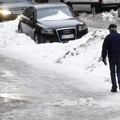 Jalankulkija etsii turvallista reittiä jäisellä pinnalla Helsingissä