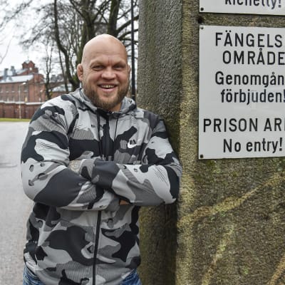 Immu Ilmen hymyilee iloisen vankilan portilla kirjoitettuaan kirjan vankien asenteista homoseksuaalisuuteen.