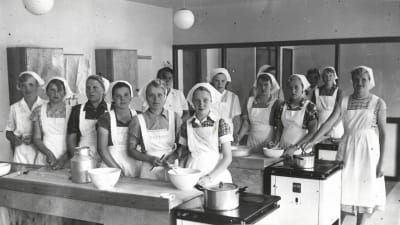 En svartvit bild på elever i skolköket i Virkby samskola.