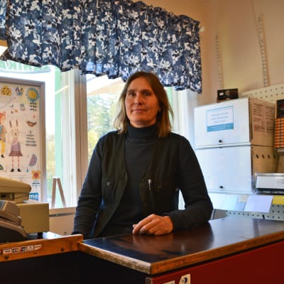 En kvinna sitter bakom en kassa.