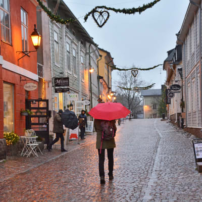En person med rött paraply går på ågatan i Borgå.