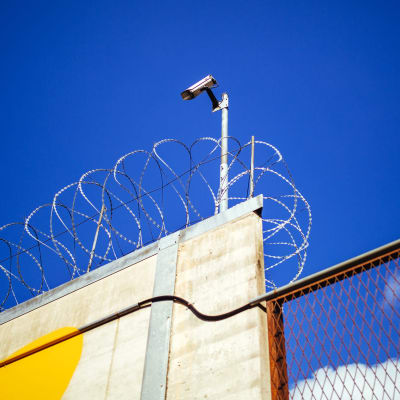 Kamera och taggtråd vid fängelse.