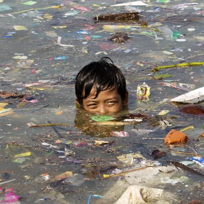 Lapsi ui roskaisessa vedessä.