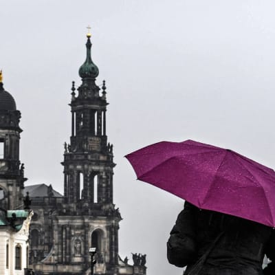 Nainen suojautuu sateelta Dresdenissä.