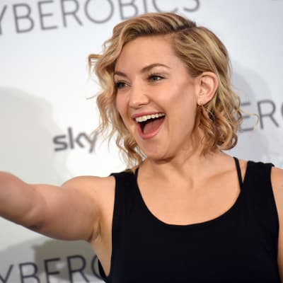 Näyttelijätär Kate Hudson vieraili World of Cyberobics -kuntokeskuksessa Berliinissä huhtikuussa 2016. Kuvassa hymyilevä Hudson osoittaa sormella eteenpäin.