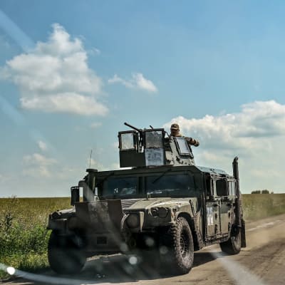 Ukrainalainen sotilasajoneuvo ajaa peltojen ympäröimällä tiellä.