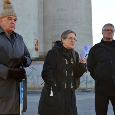 Tre människor, en kvinna och två män, står framför silorna i Vasa.