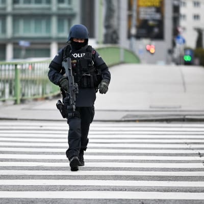 Aseistettu poliisi kävelee kadulla Wienissä.