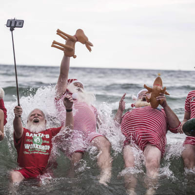 Joulupukkipukuiset poseeraavat meressä