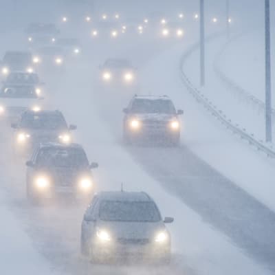 Autoja ajaa lumisateessa