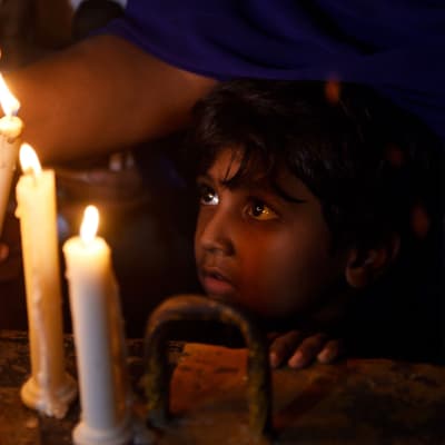 Srilankalainen lapsi katselee muistokynttilöitä.