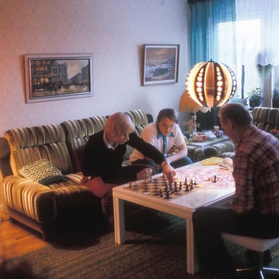 Ruotsinsuomalaiset pelaavat shakkia kotona.
