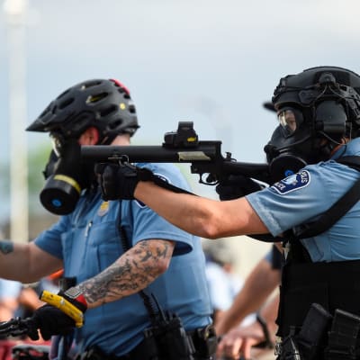 Poliisit tähtäävät aseella mellakoitsijoita Minneapoliksessa, Minnesotan osavaltiossa Yhdysvalloissa.