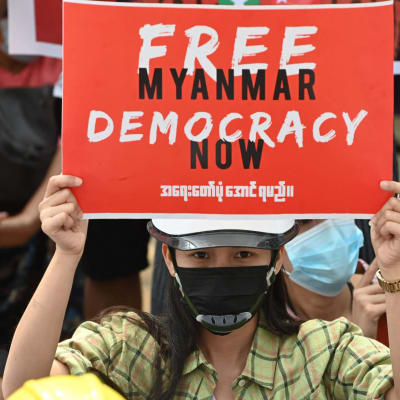Mielenosoittaja pitelee sotilasvallankaappausta vastustavaa kylttiä Yangonissa.