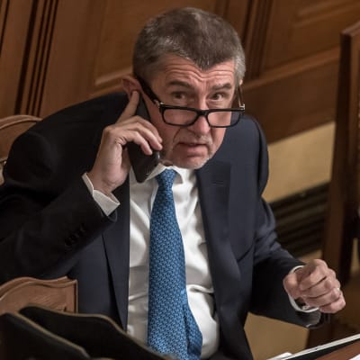 Tšekin pääministeri Andrej Babis parlamentissa puhelin korvallaan.