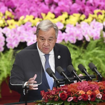 YK:n pääsihteeri Antonio Guterres puhuu, taustalla on värikkäitä kasveja.