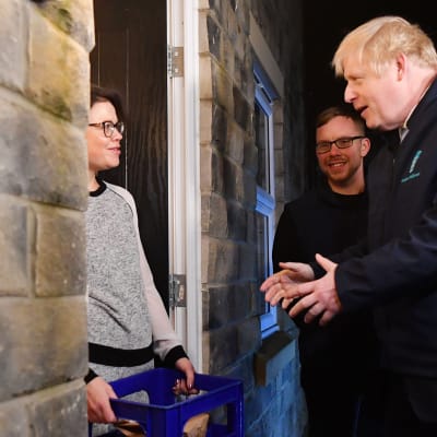 Britannian pääministeri Boris Johnson kotiinkuljettaa maitoa Debbie Monaghanille Guiseleyssä, Leedsissä 11. joulukuuta