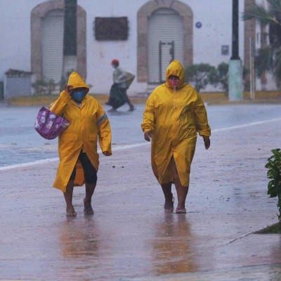 Ihmisiä kadulla vesisateessa Tiziminissä Meksikossa.