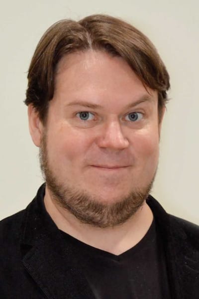 Porträttbild på en man med skägg och svart t-shirt.