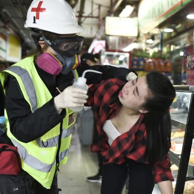 En kvinna som fått tårgas i ansiktet får första hjälpen