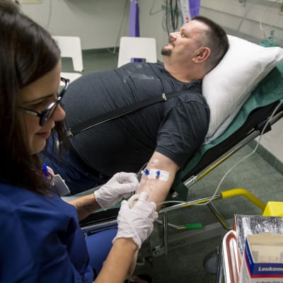 Man får vätska intravenöst genom venkateter. Sjuksköterska håller nålen på plats.