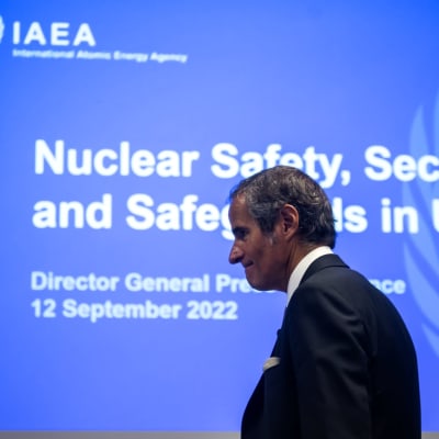 IAEA:n pääsihteeri Rafael Grossi kävelee kokouksessa. Taustalla sininen seinä, jossa valkoista tekstiä.