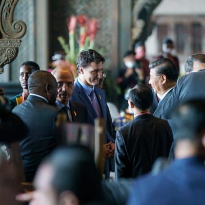Xi Jinping ja Justin trudeau juttelevat tulkin välityksellä väenpaljoudessa