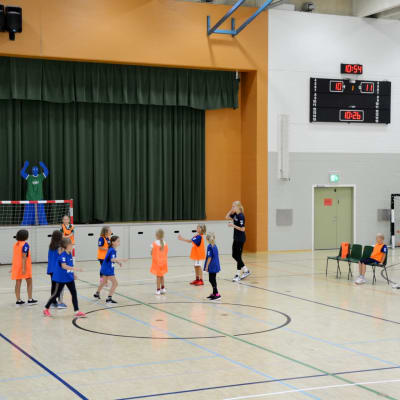 juniorer spelar handboll i en idrottshall.