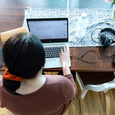 En person jobbar på sin laptop vid sitt matbord.