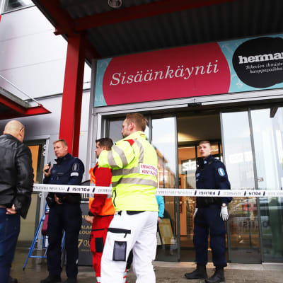 En av köpcentret Hermans ytterdörr. Utanför dörren syns räddningspersonal om en civilklädd person. 