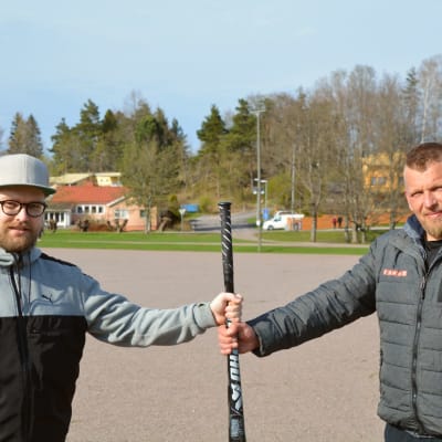 Hannu Sääskilahti i grå tröija och keps håller i ett bobollsträ tillsammans med Matti Pelander i grå jacka. 