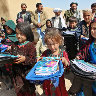 En grupp afghanska flyktingbarn visar upp sina skolväskor på ettflyktingläger i Pakistan.