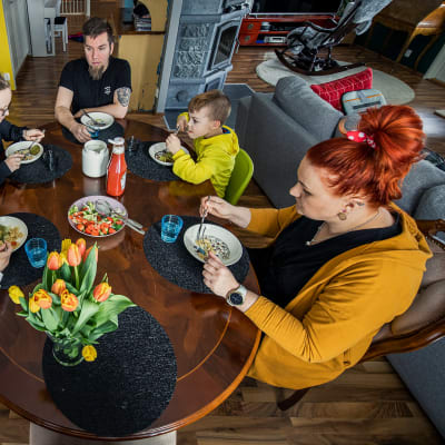 Perhe ruokailee saman pöydän äärellä.