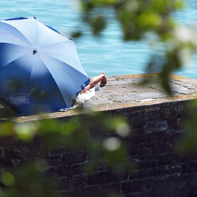Nainen on piiloutunut sinisen sateenvarjon suojaan Saksan Lindaussa.
